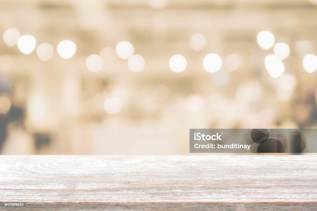Wood table top and blurred restaurant interior background with vintage filter. Wood table top background - can used for display or montage your products. Focus On Foreground Stock Photo