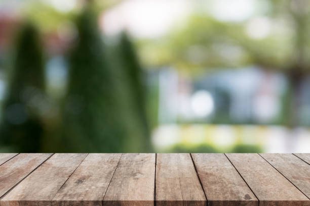 istock Wood table top and blurred garden and tree background. 647209702