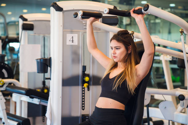 istock Woman using weight machine in gym 647210378