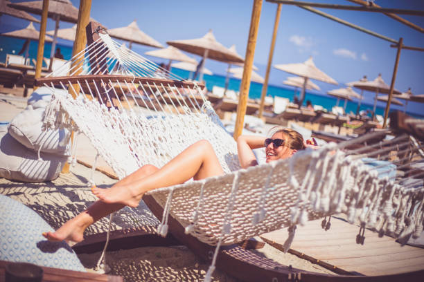 istock Happy young woman lying in hammock on tropical beach 647210458