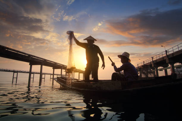 istock Silhouette of fishermen using nets to catch fish 647214942