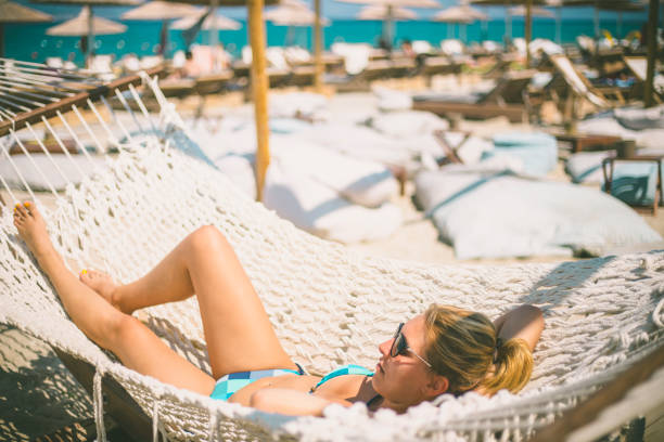 Happy young woman lying in hammock on tropical beach