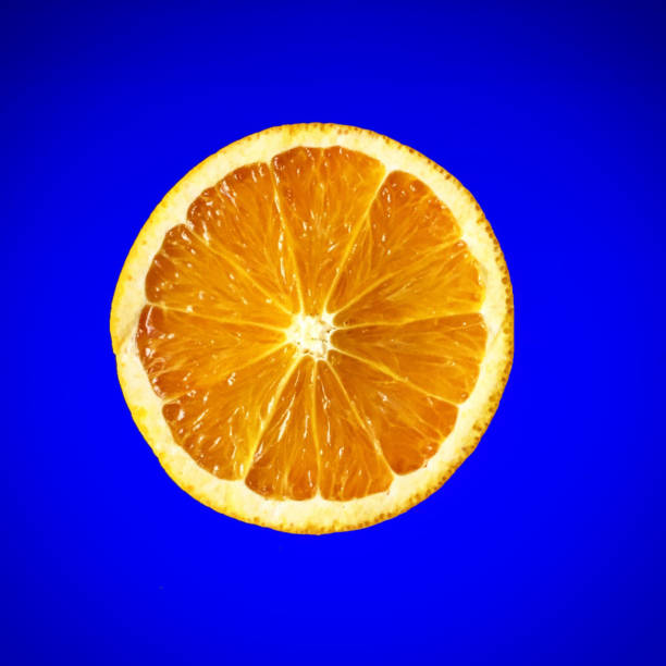 istock Slice of orange fruit half close-up on blue background 647218352