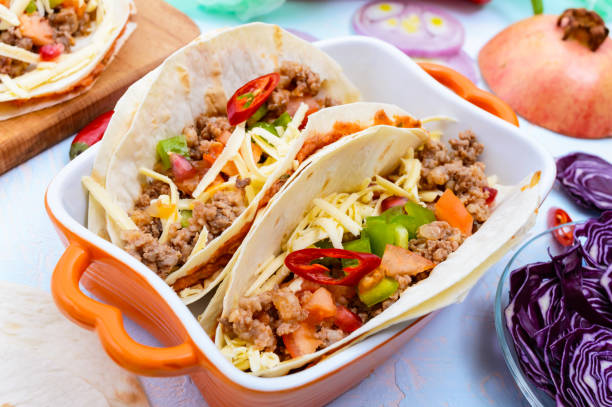 istock Spicy Mexican tacos with minced meat, mashed beans, vegetables, grated cheese 647221266