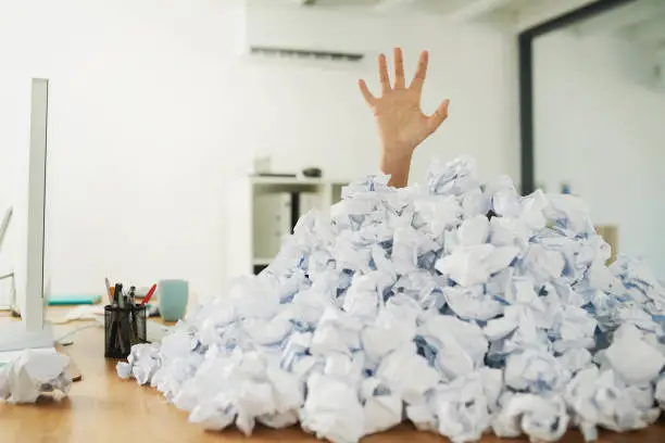 Shot of an unidentifiable businesswoman drowning under a pile of paperwork in the office