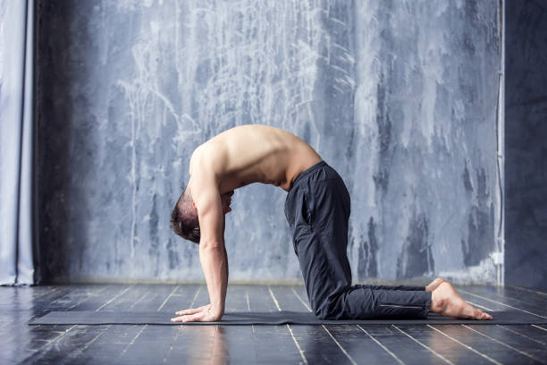 Yoga men workout on black mat. Young yogi men practices yoga asana chakravakasana - bird pose in urban studio. Yoga men workout on black mat. cat pose yoga stock pictures, royalty-free photos & images