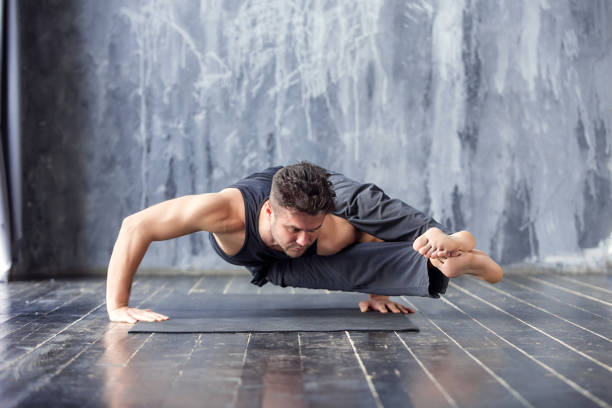 istock Young man doing an asana ashtavakrasana 647227980