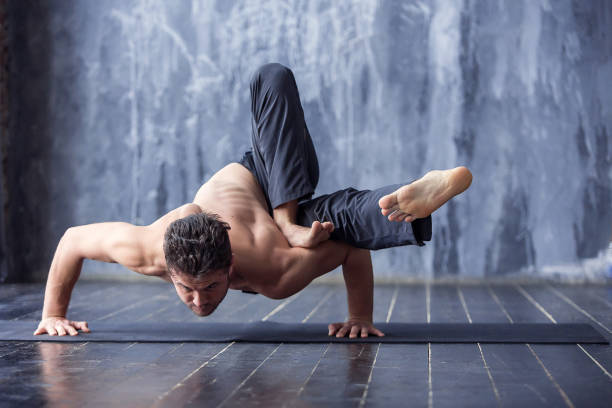 istock Young man doing an asana ashtavakrasana 647228370