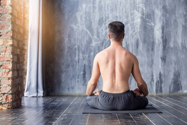 Yoga men workout in studio on black mat, back view stock photo