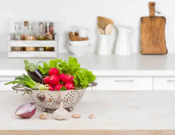 Photo of Fresh vegetables on wooden table over blurred kitchen counter interior