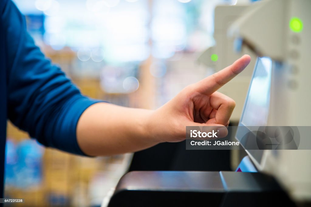 Close up of a woman using a self checkout machine Close up of a woman's hand as she uses a self checkout machine. Osaka, Japan. June 2016 Self Checkout Stock Photo