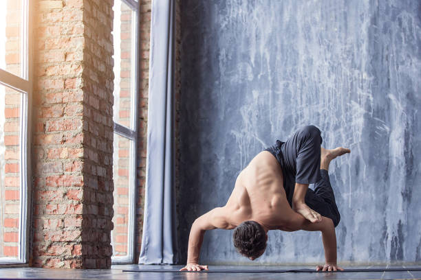 istock Young man doing an asana ashtavakrasana 647231634