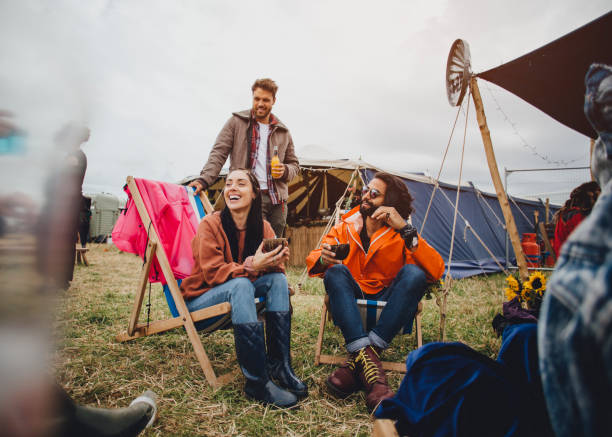 Chilling At The Festival Friends are relaxing outside of their tent at a music festival. They are talking and enjoying alcoholic drinks. music festival camping summer vacations stock pictures, royalty-free photos & images