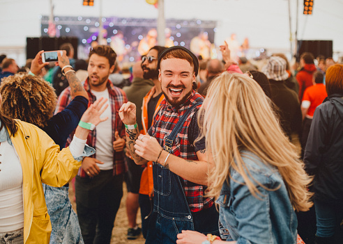Friends are dancing in a performance tent at a music festival.
