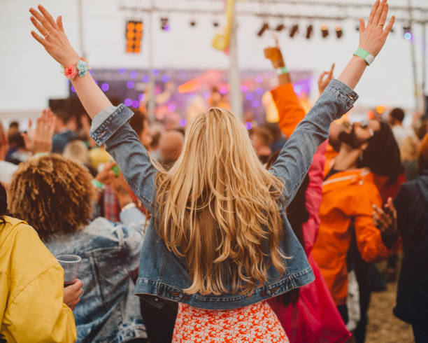 Festival Freedom Young woman with blonde hair is dancing with her friends in a performance tent at a music festival. She has her arms outstretched and is watching the performance. hand raised photos stock pictures, royalty-free photos & images