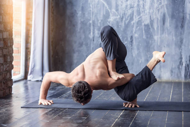 istock Young man doing an asana ashtavakrasana 647235580