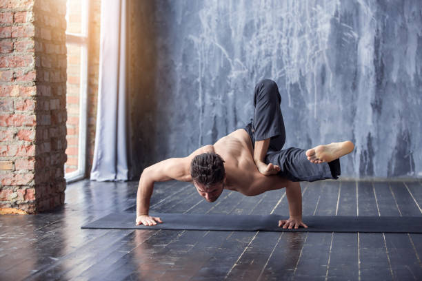 Young man doing an asana ashtavakrasana