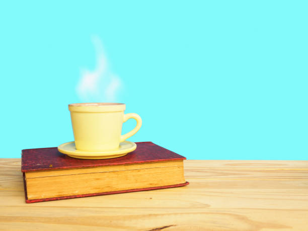 istock Coffee cup and old book on wooden table of blue background 647242896