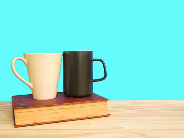 istock Coffee cup and book on wooden table of blue background 647242914