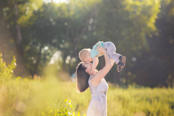 Cute little toddler boy holding his mother's hand. Adorable child walking with his mom in the park on sunny summer day. stock photo