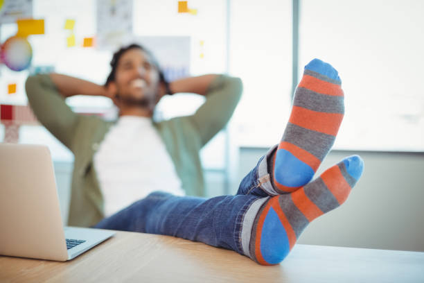 Male graphic designer relaxing with feet up at desk Male graphic designer relaxing with feet up at desk in office feet up stock pictures, royalty-free photos & images