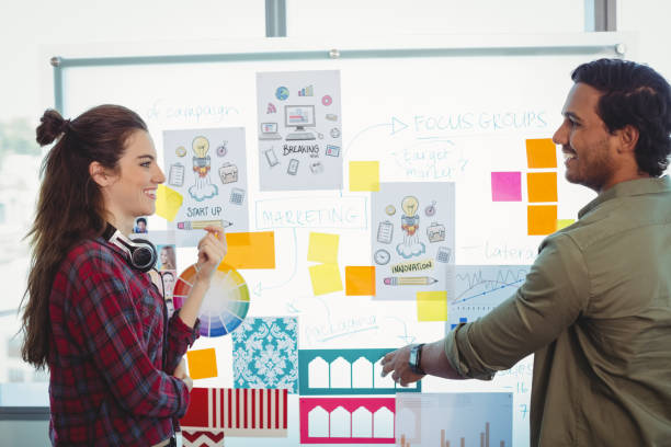 istock Male and female graphic designers discussing over sticky notes 647273416