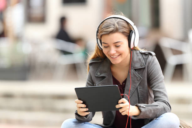 fille d’apprentissage en ligne avec une tablette et casque - digital tablet women enjoyment happiness photos et images de collection