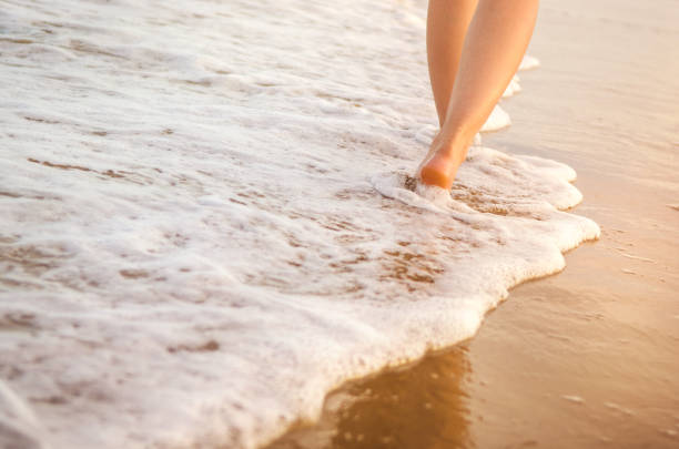 istock Woman walking on wet sandy beach 647284456