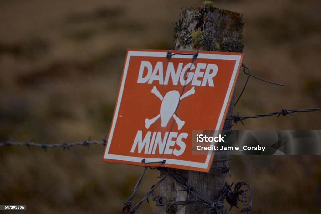 Danger Mines!! Mine Sign on the fence of an active minefield in the Falkland islands Land Mine Stock Photo