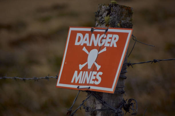 Danger Mines!! Mine Sign on the fence of an active minefield in the Falkland islands land mine stock pictures, royalty-free photos & images