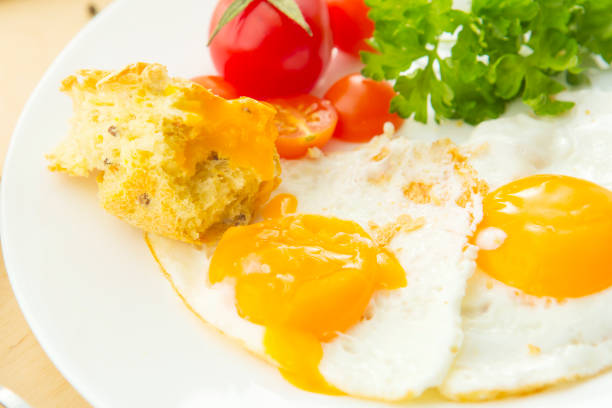 Fried eggs with white bread on plate on wooden table