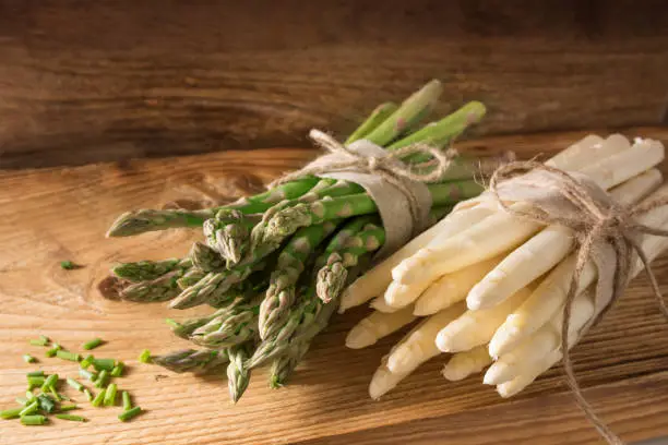 Fresh green and white asparagus with chopped parsley on rustic wood
