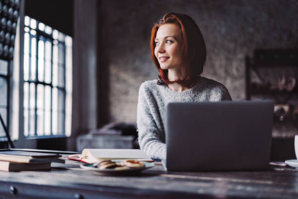 Young woman working in a loft apartment with a laptop computer