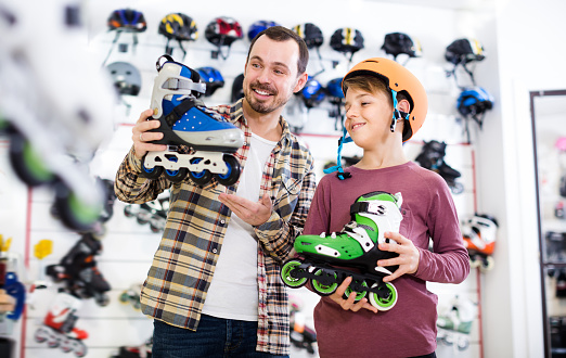 Man and son boasting purchased roller-skates in sports store