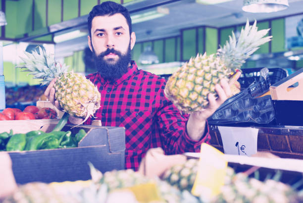 istock Young male seller offering pineapples 647308850