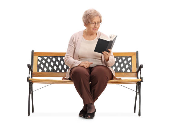 istock Senior sitting on a bench and reading a book 647320034