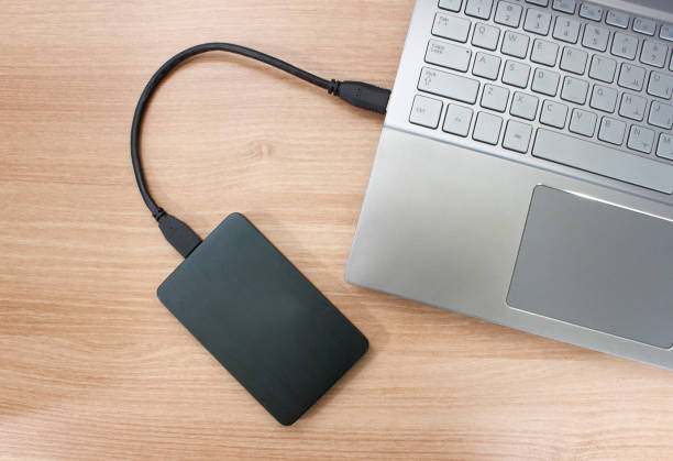 istock Hard drive connected to the Laptop computer on wood texture 647324622