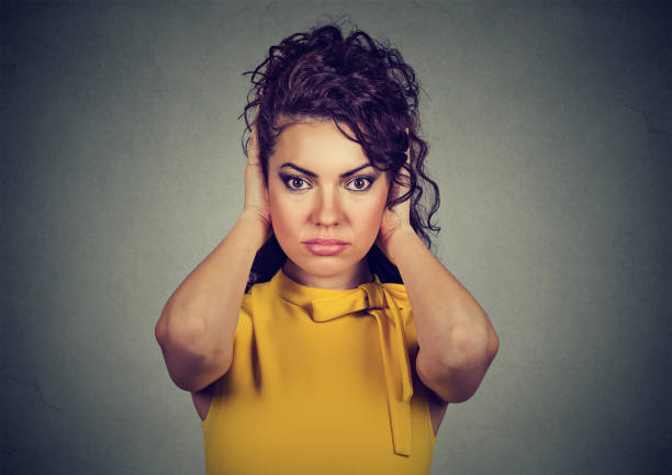 istock woman covering with hands her ears 647328112