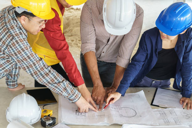istock business people group on meeting and presentation with construction engineer architect looking building model and blueprint plans 647329274