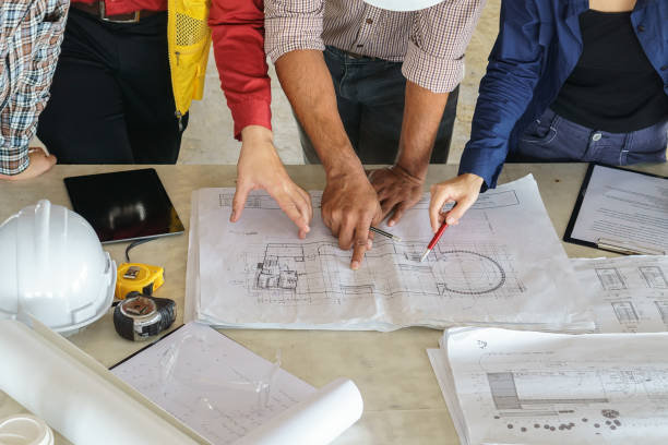 istock business people group on meeting and presentation with construction engineer architect looking building model and blueprint plans 647330874