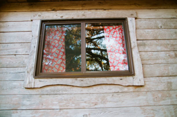 istock Cabin window framed by wood and a red and white curtain 647331510