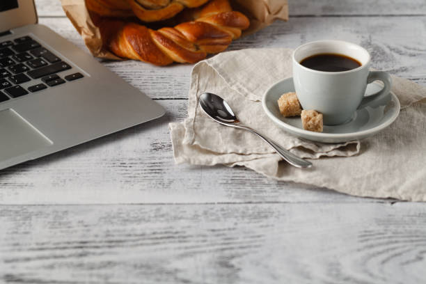 istock Fresh pastry and cup of brew coffee on table in office with laptop 647337948
