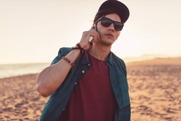 Charming young man on the beach , talking on his phone