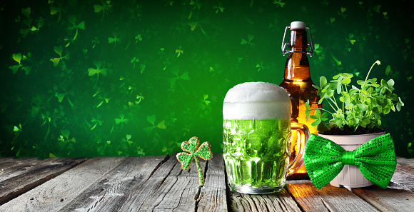 Green Beer In Glass With Bottle And Clovers On Wooden Table
