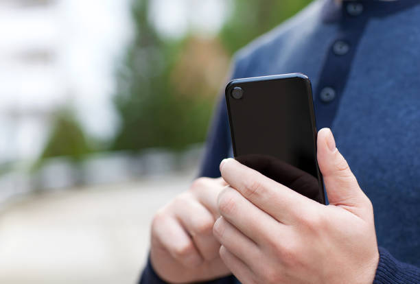 istock man holding black touch phone in the street 647343684