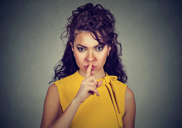 istock Secretive woman with finger on lips asking quiet 647343976