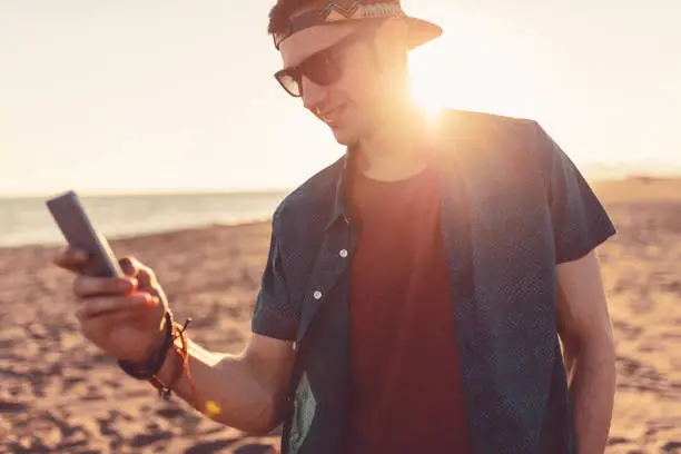 Attractive young man playing pokemon go on the beach, pokemon go