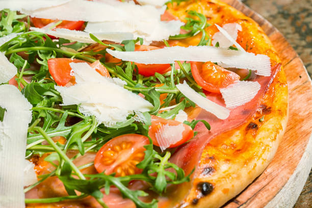 istock Pizza with ham, tomatoes, parmesan and arugula 647348560