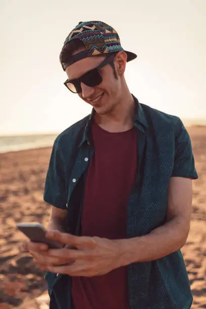Handsome young man catching pokemons on the beach, pokemon go