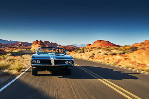 hombre conduciendo coche antiguo a través del desierto - coche de coleccionista fotografías e imágenes de stock